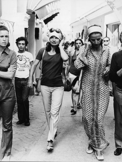 Jackie Onassis walks through a busy street in Capri, Italy, in the early 1970s.