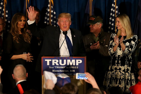 Republican presidential candidate Donald Trump speaks as his wife Melania Trump and daughter Ivanka Trump look on after Primary day at his election night watch party at the Executive Court Banquet facility on February 9, 2016 in Manchester, New Hampshire.