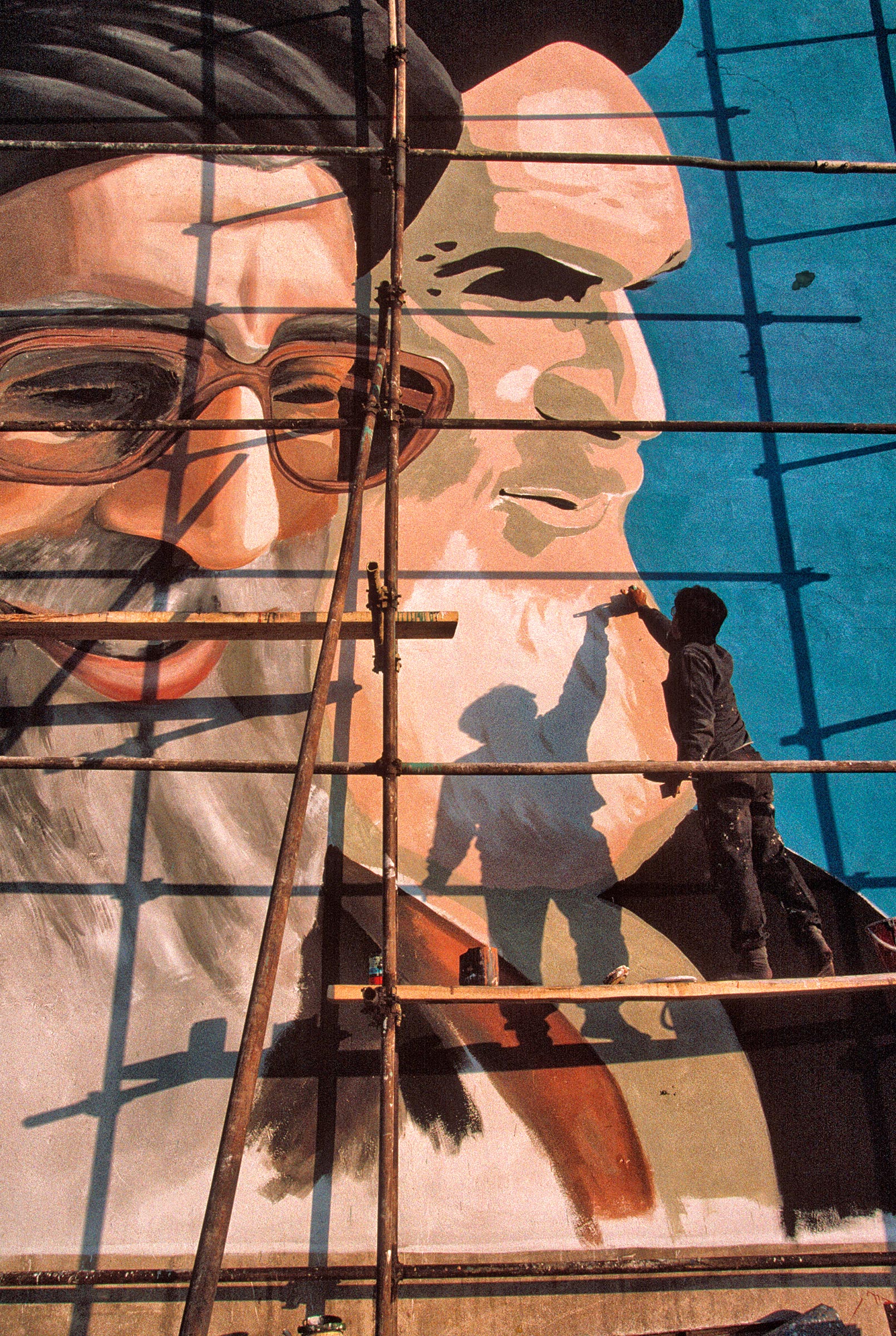 A painter works on a Tehran mural of Khamenei, left, and Iran’s first Supreme Leader, Ruhollah Khomeini