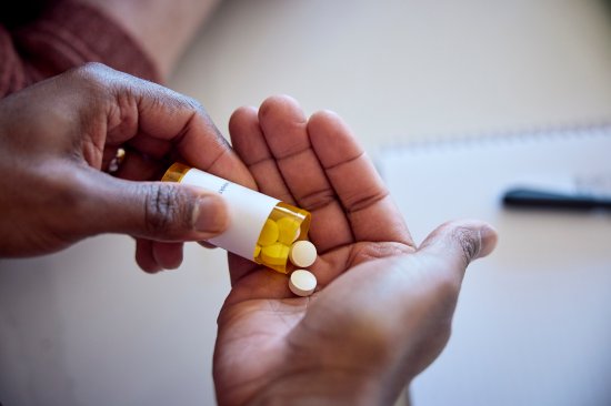 Man pouring pills into hand