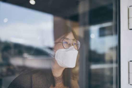 Woman looking through window with mask