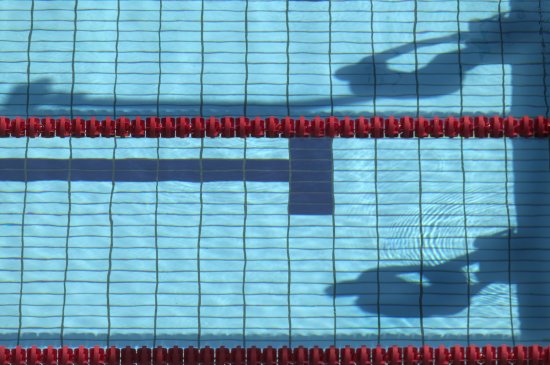 Shadow in swimming pool of swimmers on starting blocks