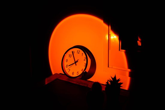 Wall clock in office desk with big sunset sun light effect.